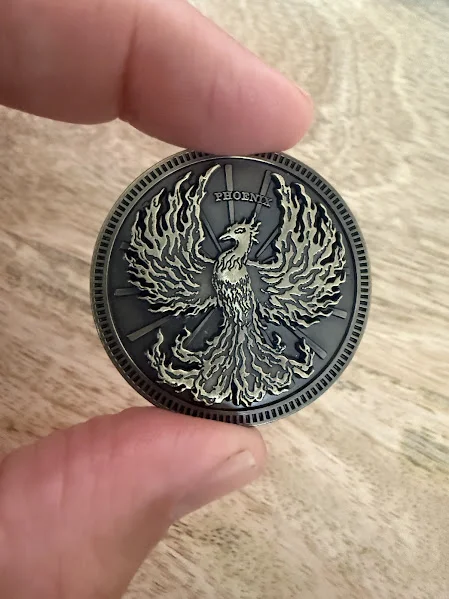 Phoenix face of the Mythic Mash coin held in hand